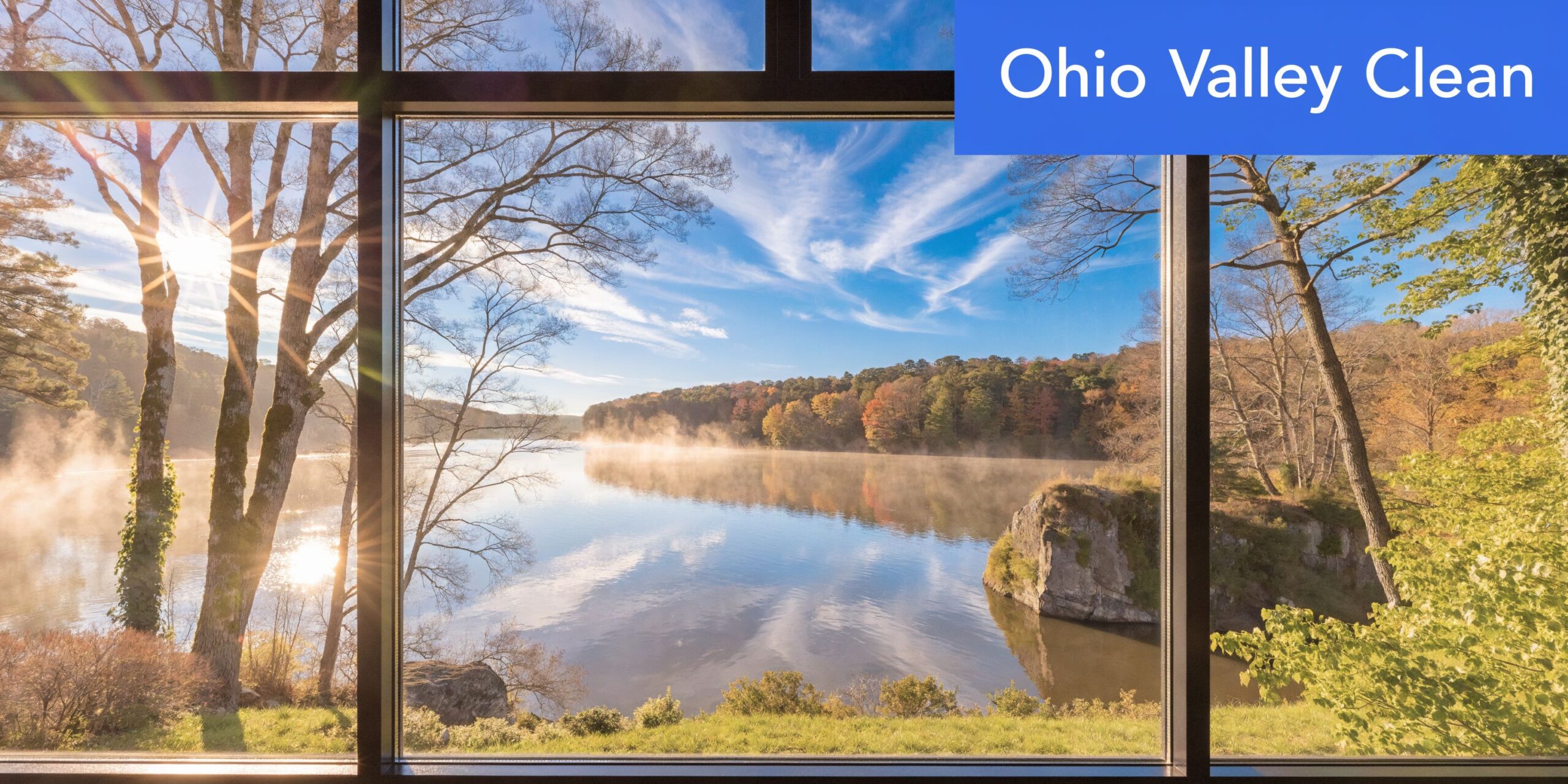 A scenic view of a misty lake framed through a clean, transparent window pane during autumn.